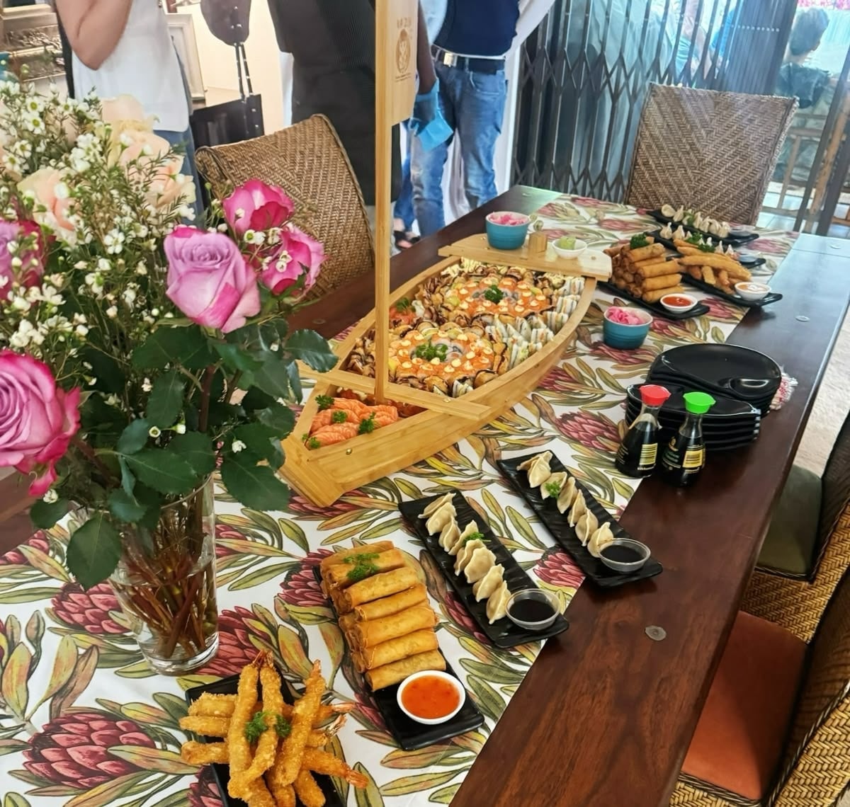 A sushi boat with tempura prawns, spring rolls and gyoza on a dining table
