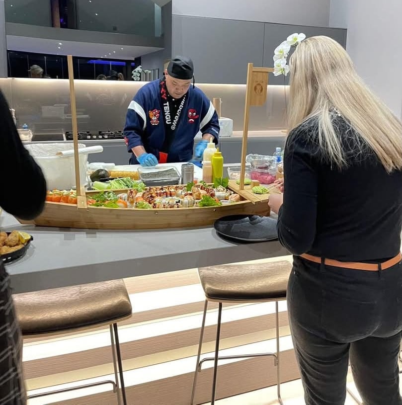 A Wa Zen chef making sushi at a kitchen island while a guest watches