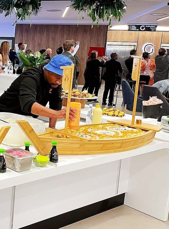 A chef finishing a sushi boat at a busy function