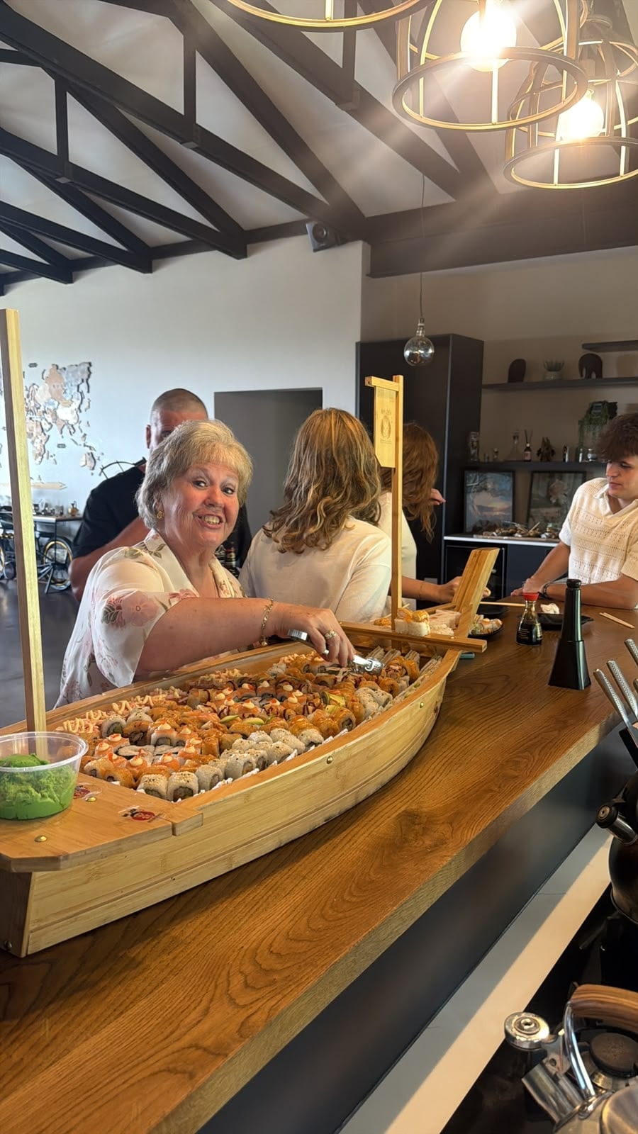 A guest helping themselves to sushi from a bamboo boat