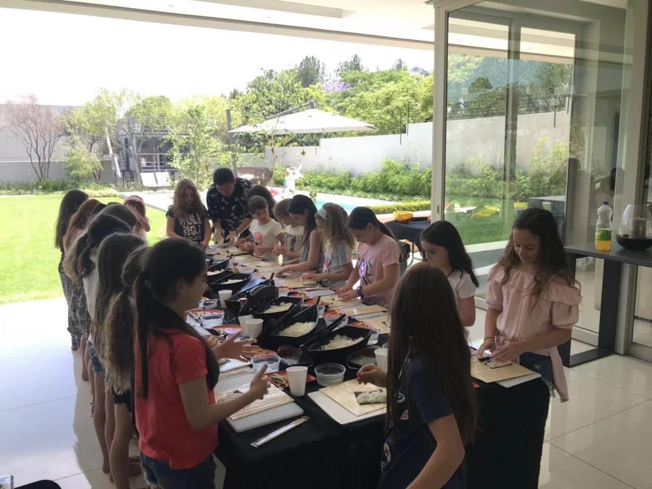 Children rolling sushi with a Wa Zen chef at a garden party