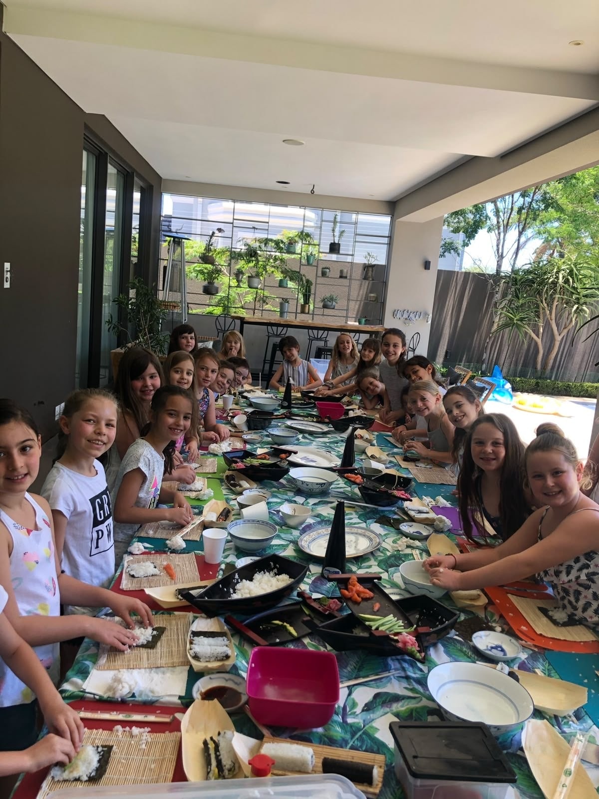 Children at a sushi party, smiling over their rolling mats