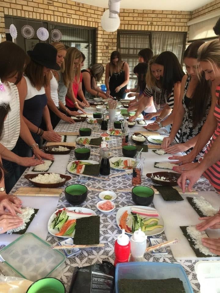 A group of adults rolling their own sushi at a long table